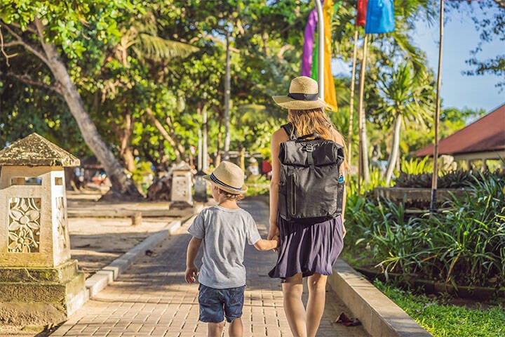 Mom and son travelers discovering Sanur, Bali, wearing sun hats.