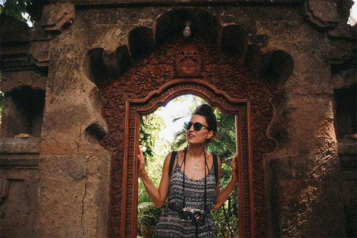 A young woman, solo tourist, walking through the old Hindu temples in Ubud, on the island of Bali, Indonesia