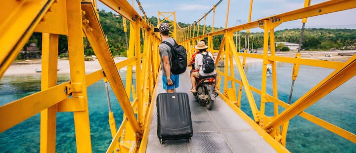 Traveller with suitcase crossing the yellow bridge that connects Nusa Lembongan and Nusa Ceningan
