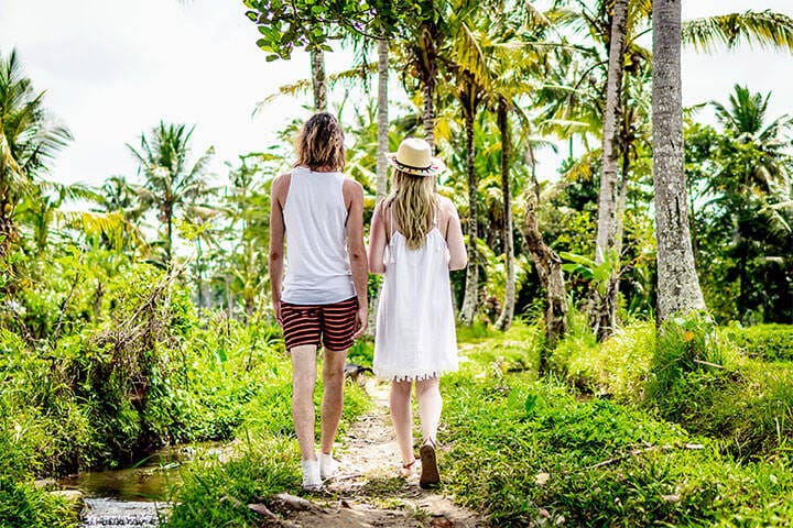 Young couple on honeymoon walking among rice fields on Bali Island