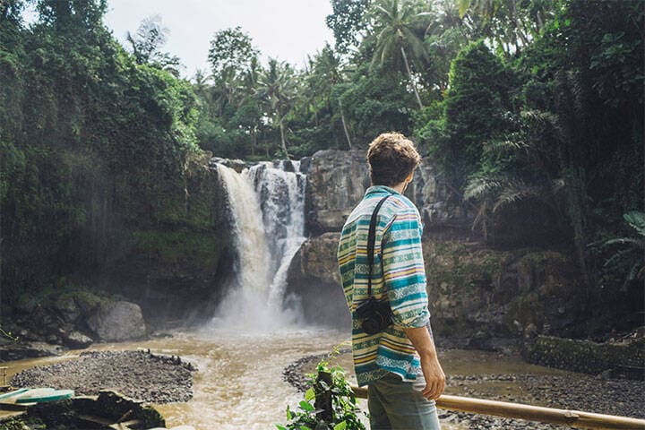 A young man in a colourful linen shirt at Tibumana waterfall in Bali
