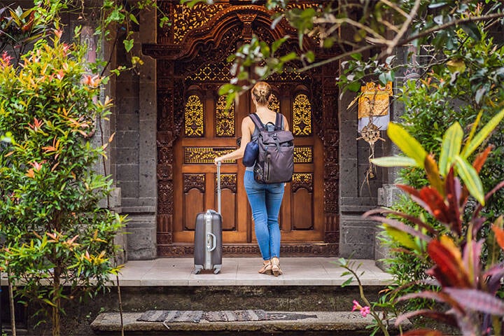 A young traveller arrives at a Bali hotel with her suitcase and backpack