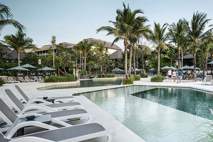 Pool area and palms trees at The Anvaya resort in Canggu, Bali