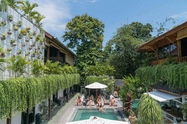 Young people relaxing by the pool at  The Farm Hostel in Canggu, Bali