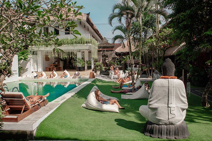 Young people relaxing on bean bag chairs by the pool of Puri Garden Hotel and Hostel Ubud, Bali