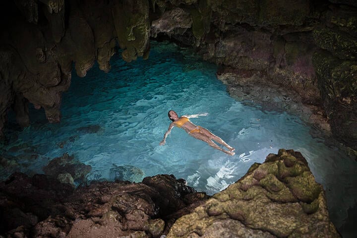 Woman swimming on her back in the natural rock pool, Dolly Beach Spa