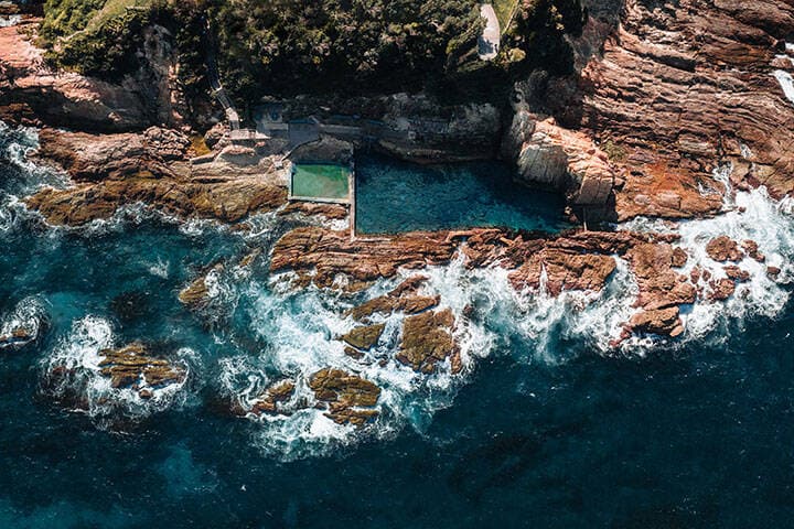 Aerial drone view of Blue Pool in Bermagui during sunrise sunset with blue sky and reflection. New South Wales, Australia