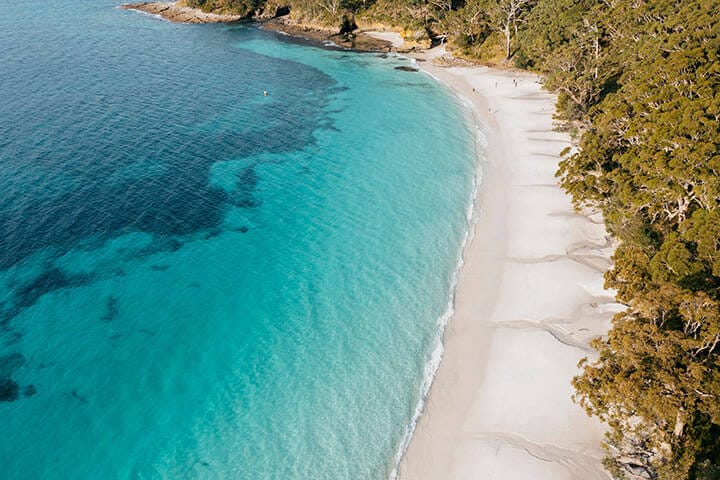 Friends enjoy a walk along Murrays Beach at Jervis Bay, NSW