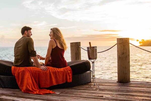 Couple enjoying sunset on deck overlooking water, Samoa