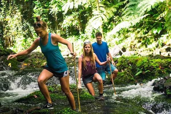 Travellers hiking on rainforest waterfall in Samoa