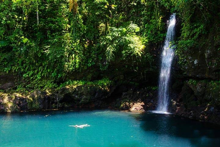 Travellers swimming in waterfall lagoon Afu Aau, Samoa