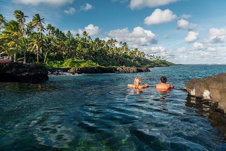 Couple swimming, overlooking the water in Samoa
