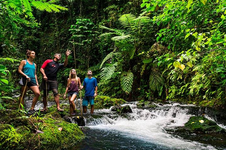 Travellers hiking on rainforest waterfall in Samoa