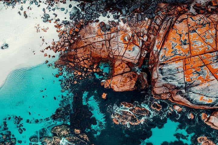 Drone Aerial of White Sand Beach and Orange Lichen Covered Boulders at Bay of Fires, Tasmania, Green Blue Water