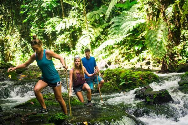 Tourists crossing river path on hike in Samoan rainforest
