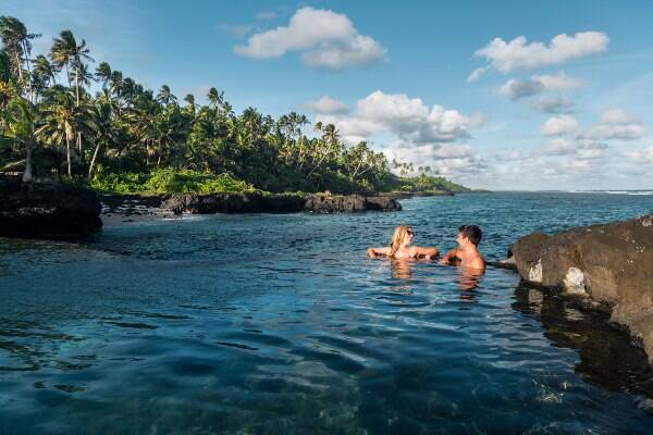Couple swimming in blue ocean at Samoan beach