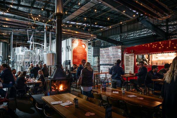Interior shot of group of people at Capital Brewing Co with food truck and brewing tanks in background