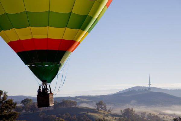 Coloured  hot air balloon in sky over Canberra and with hills and Black Mountain behind