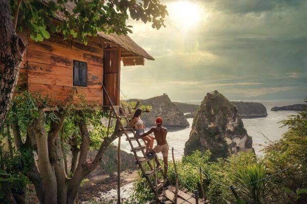 Hiking couple taking in the view at Rumah Pohon Treehouse at Nusa Penida Island near Bali by Darren Lawrence