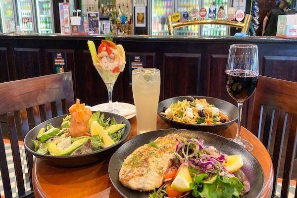 Fresh fish and salad dishes on table with drinks for patrons to enjoy lunch at Fiddlers Green, Darwin.