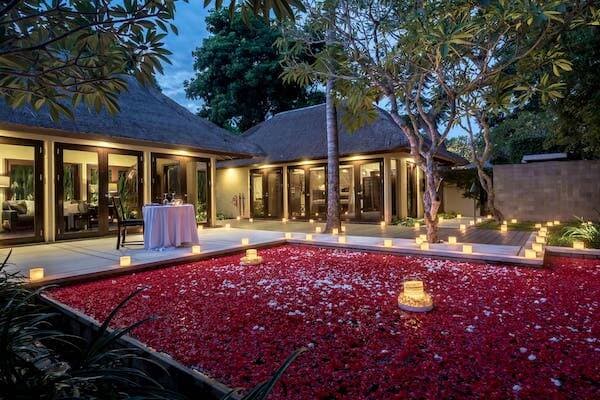 Outdoor dining table for two overlooking rose petal covered private swimming pool at Kayumanis Nusa Dua Private Villa and Spa, Bali