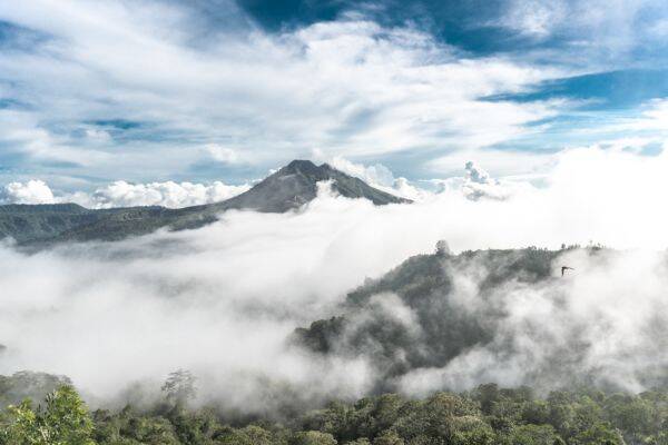 Green trees and white clouds over Mount Batur in Bali by Polina Kuzovkova