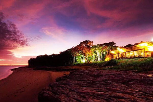 Night view of beachfront resort and sandy beach waves crashing while the sun sets at Pee Wees at the Point.