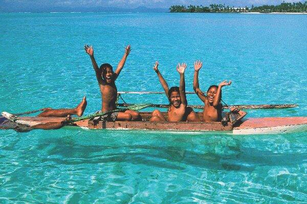 Samoan children playing in wooden boat in ocean