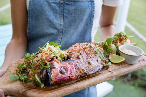 Server presenting freshly cooked fish with seasonings and marinade at Snapper Rocks restaurant, Darwin.