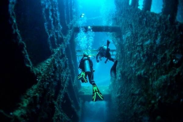 Swimmers' scuba diving in shipwreck underwater in Vanuatu