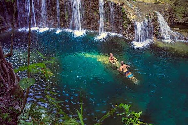 Swimmers floating in waterfall lagoon in Vanuatu