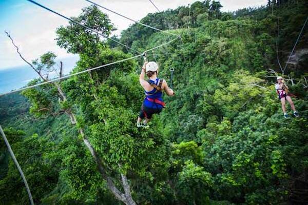 Traveller ziplining over lush green trees in Vanuatu