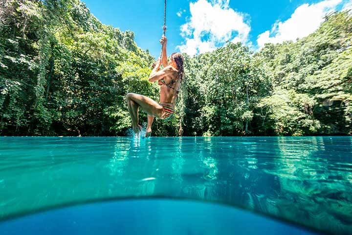 A woman on a rope swing over Riri Blue Hole, Espiritu Santo, Vanuatu