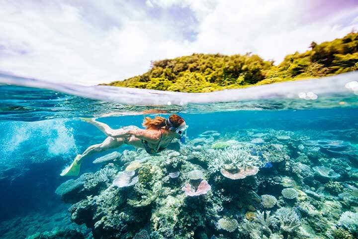 A woman snorkelling over a coral  reef off the coast of Espiritu Santo, Vanuatu.