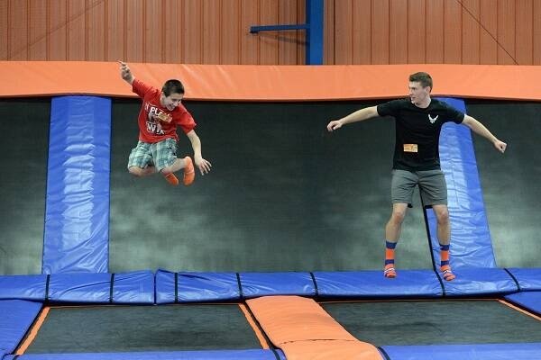 Two people airborne on trampolines at Sky Zone Alexandria, enjoying a fun activity in a lively indoor environment.