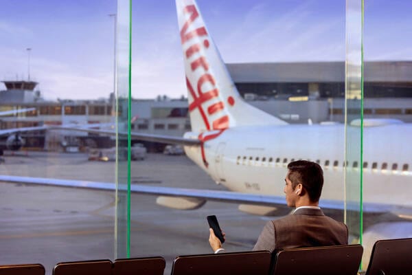 Smartly dress business woman checking in for a flight at the Virgin Australia desk. 