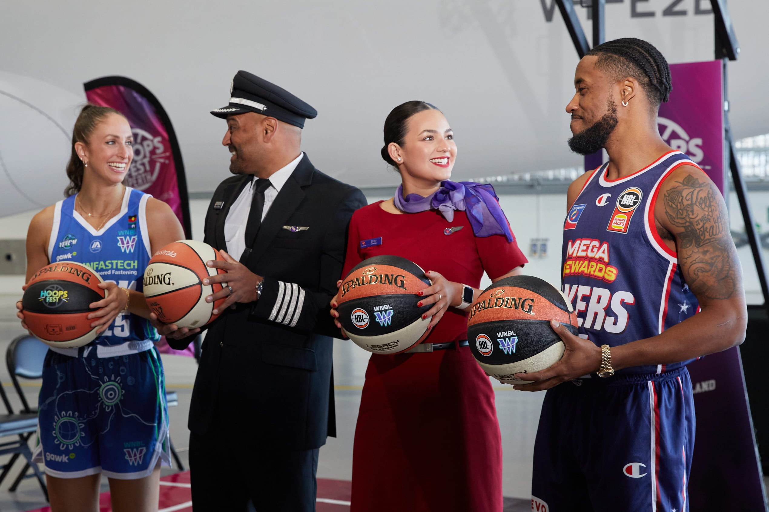 Virgin Australia cabin crew and WNBL and NBL athletes standing in front of aircraft holding basketballs.