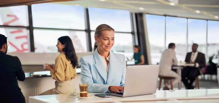Virgin Australia lounge guest working on laptop whilst drinking coffee at Sydney Airport