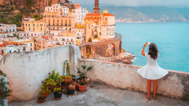Woman taking photo along Italian coastline.