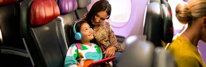 Mother and daughter watching inflight enterainment on device, travelling in economy cabin on Virgin Australia flight