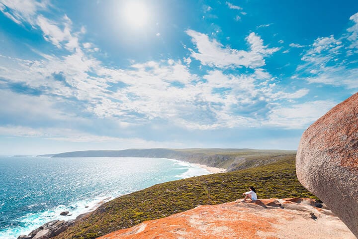 Woman sitting on the edge of the cliff at Remarkable Rocks on Kangaroo Island, South Australia  