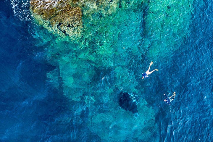 Aerial drone view of snorkelers with huge oceanic manta rays at Manta Point