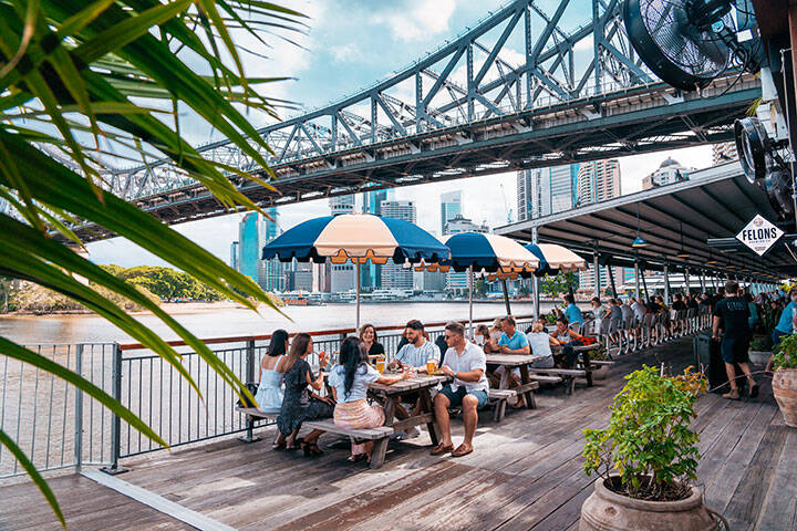 Friends enjoying drinks at the riverfront bar and restaurant in Howard Smith Wharves, Brisbane 
