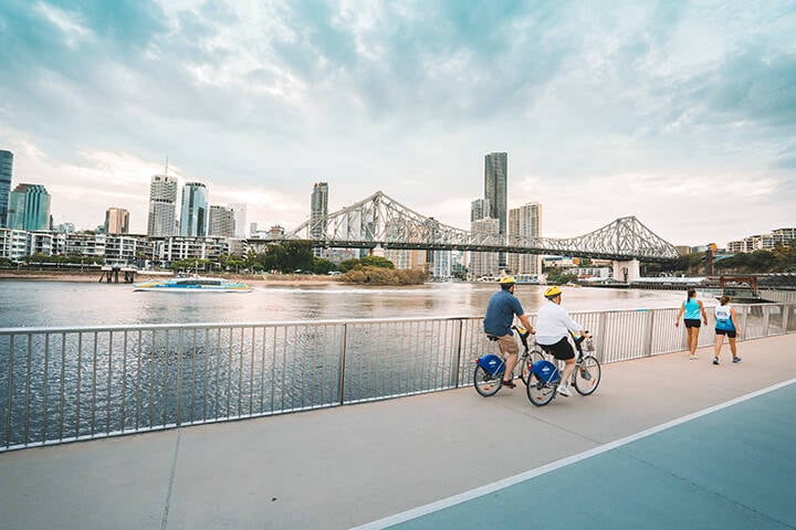 Couple cycling along the floating river walkway in Brisbane