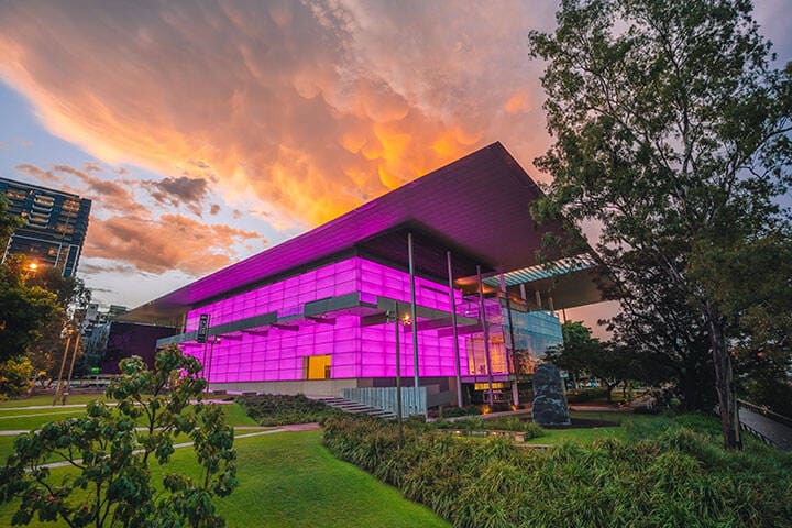 QAGOMA at sunset, coloured lights lighting up the building. 