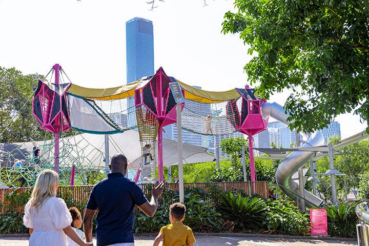 An image of a family standing in front of a playground in South Bank
