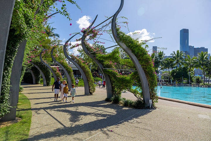 A distant shot of a family walking past a pool near the South Bank Grand Arbour 