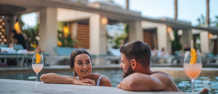 Couple having a cocktail in the pool, at The Calile Hotel