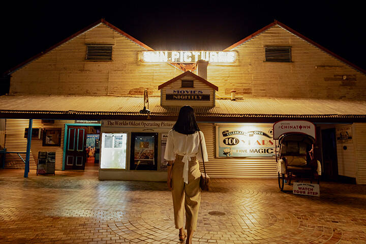 Woman standing outside of the Sun Pictures cinema in Broome at night