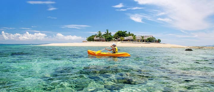 Young woman kayaking near South Sea Island, Mamanuca islands group, Fiji  